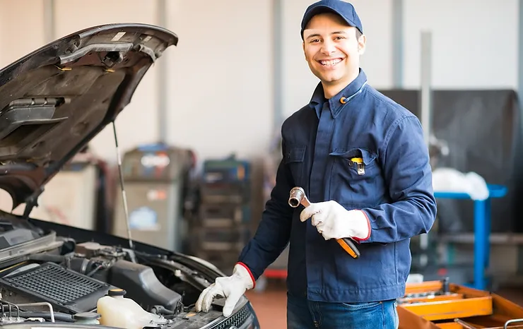 male mechanic smiling working on car